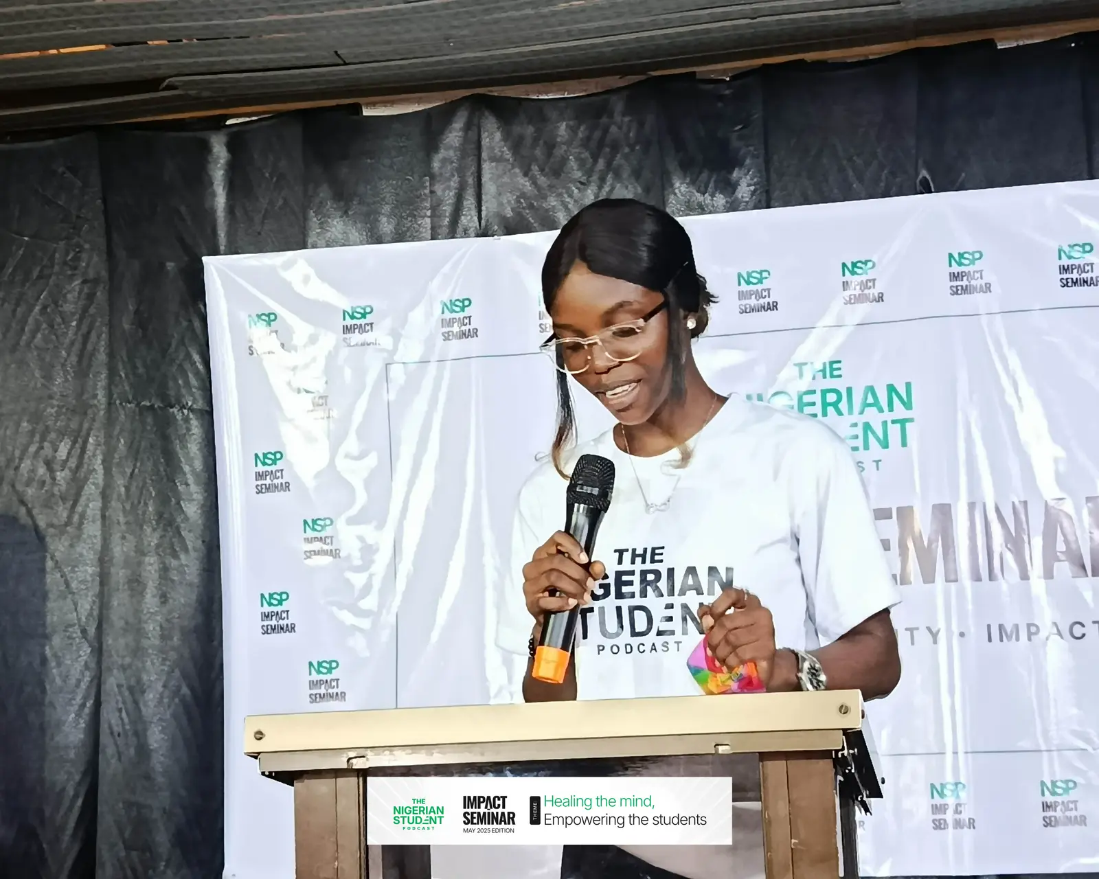 A student speaks at the podium in front of the Impact Seminar banner